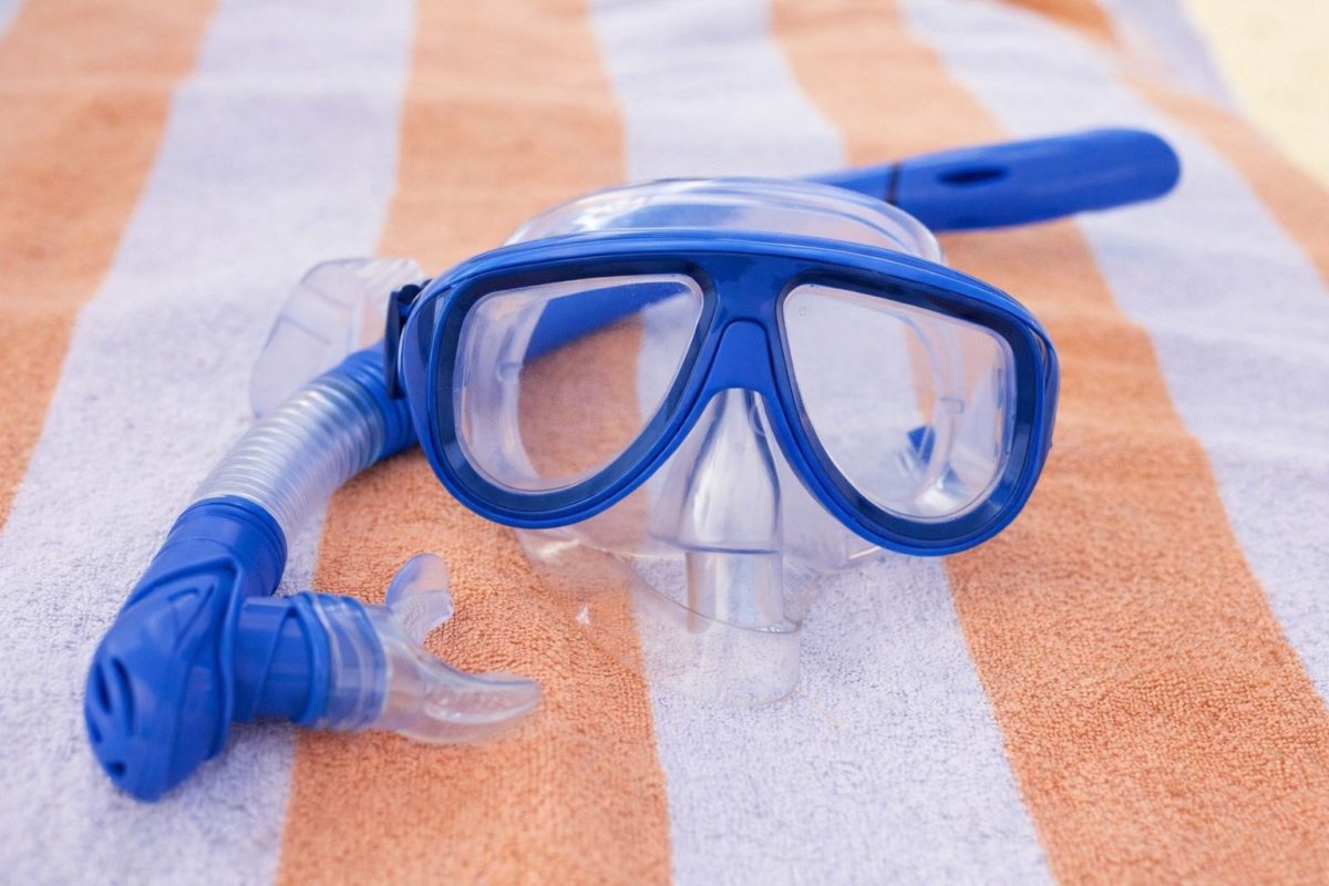 Snorkel mask fins and reef-safe sunscreen on Maui beach