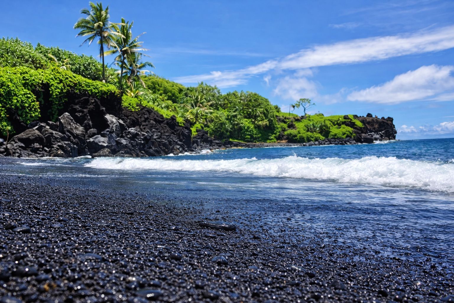 Black sand beach with sea arch and turquoise water Maui